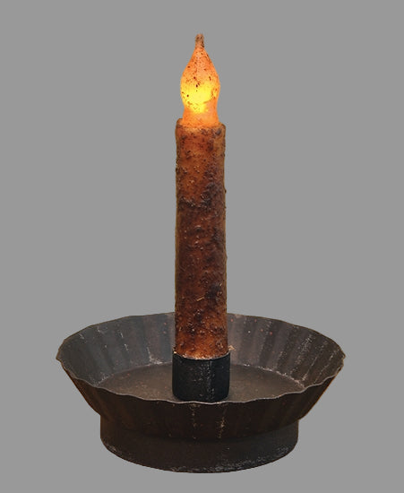 A black metal taper candle holder with a fluted design and a lit candle, set on a wooden surface.