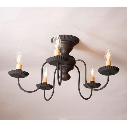 Black chandelier with five lit candles on a plain background