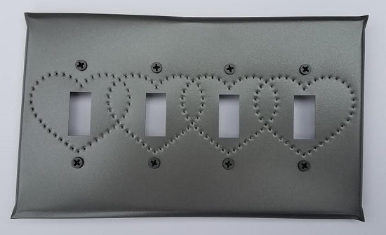 A tin quad switch plate with heart punch design, featuring a gray color and bordered by screws.