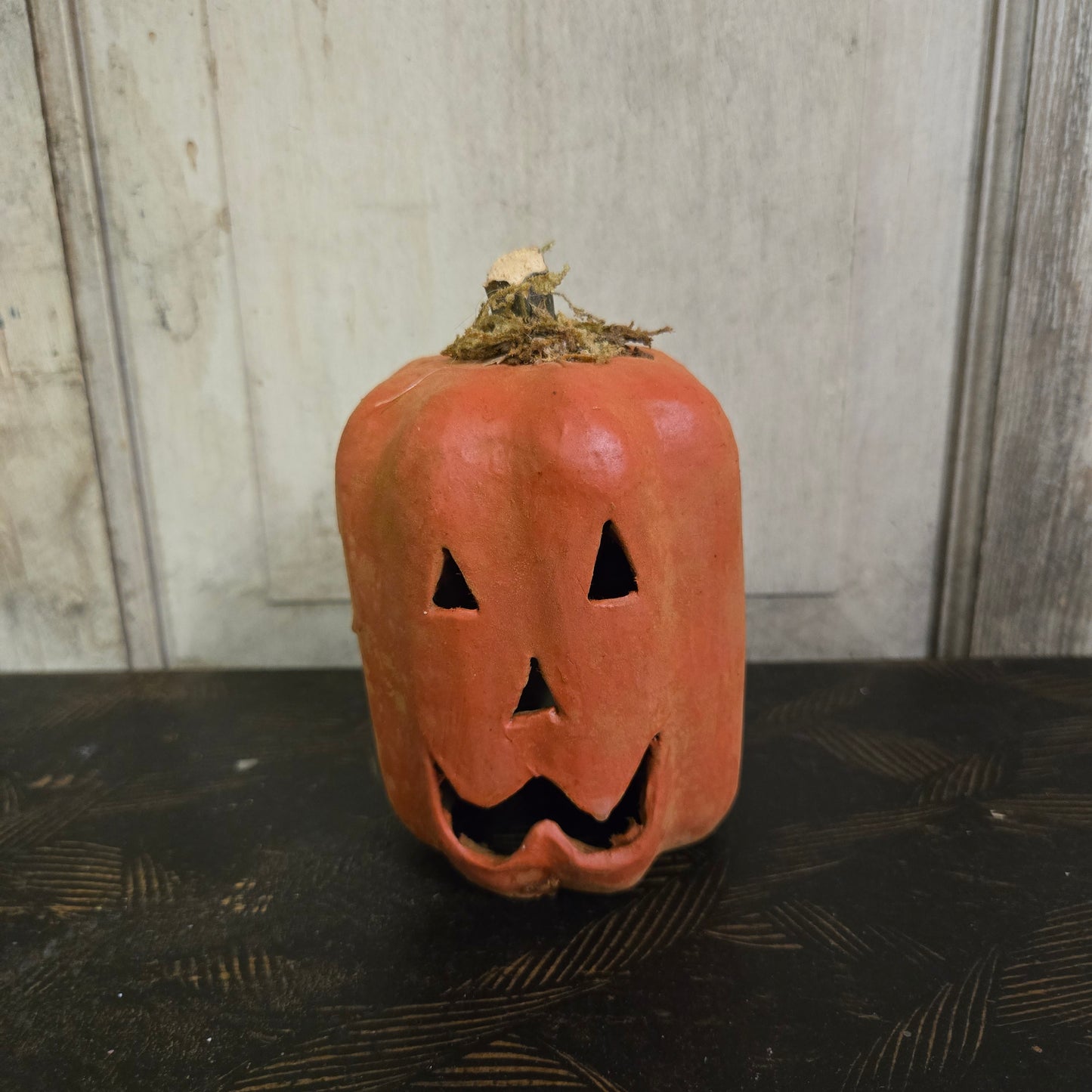 Decorative pumpkin with a carved face on a wooden surface