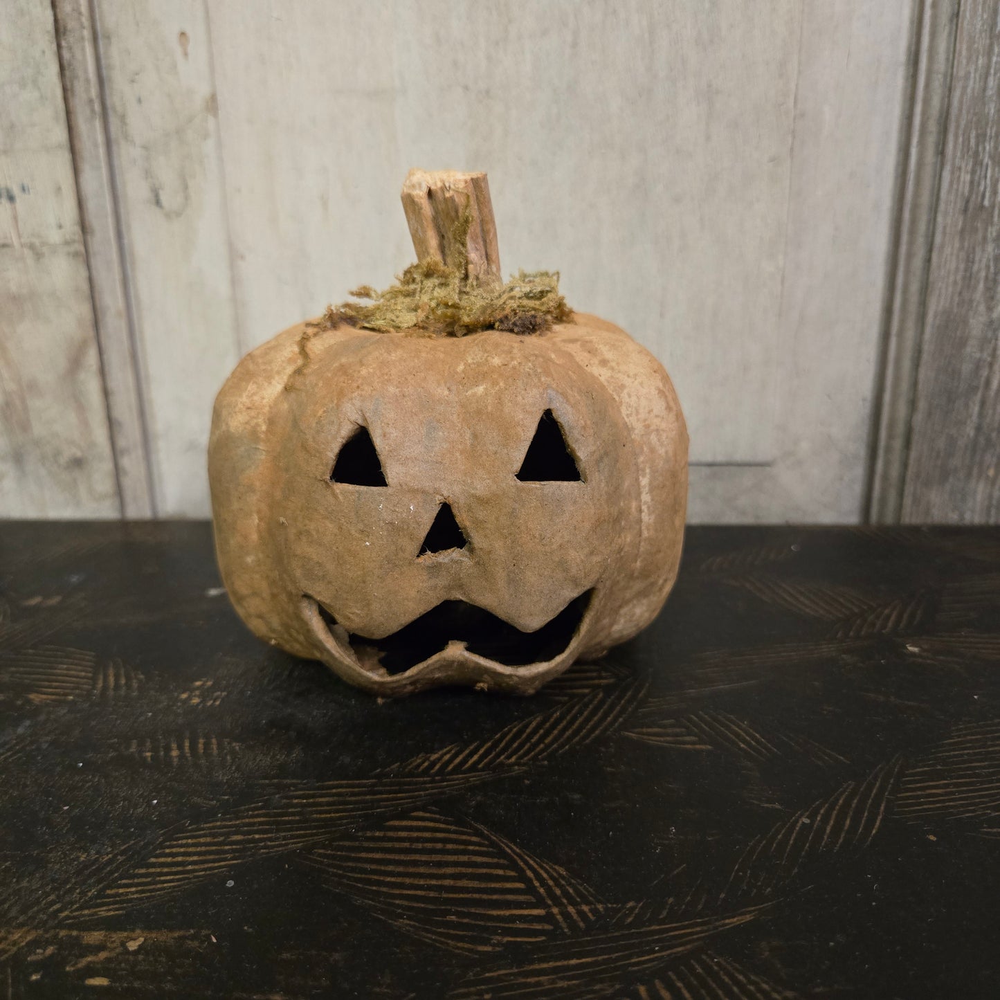 Worn-out pumpkin with a carved face on a textured surface