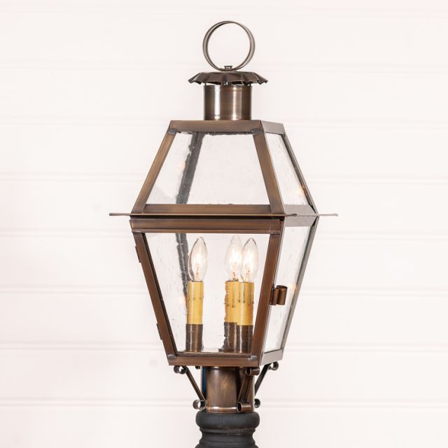 A solid antique copper outdoor post light with three lights, featuring clear glass panels and a blackened solder finish.