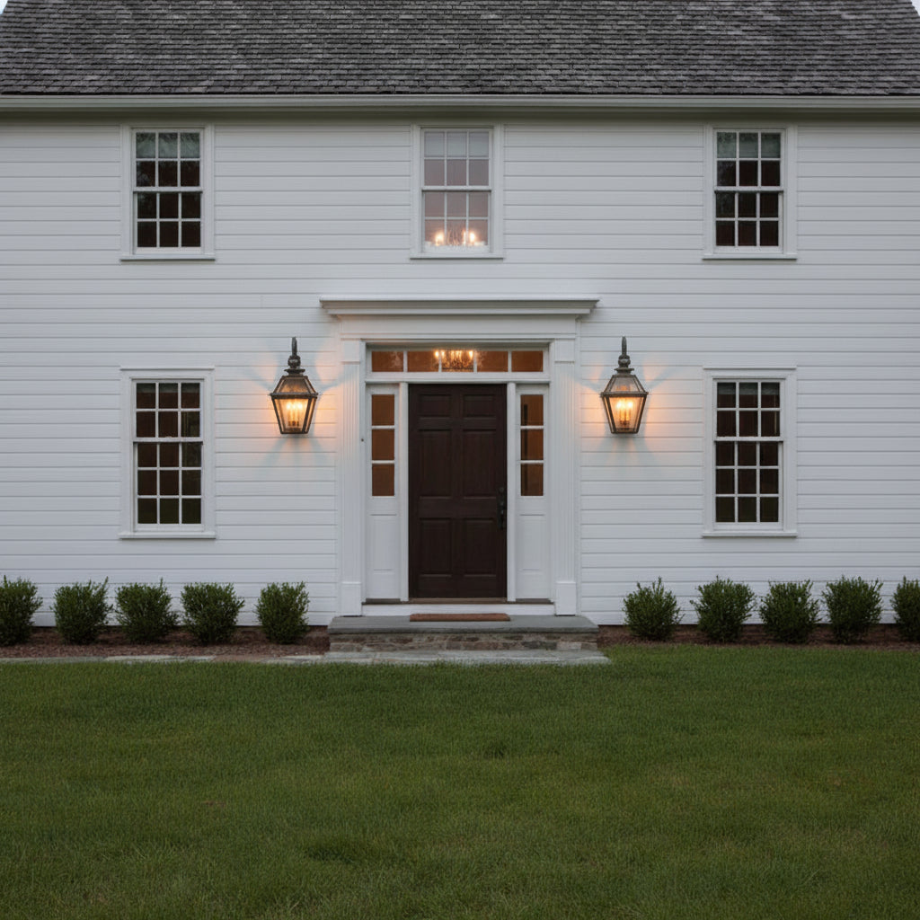 Two solid weathered brass outdoor wall lights on a colonial home.