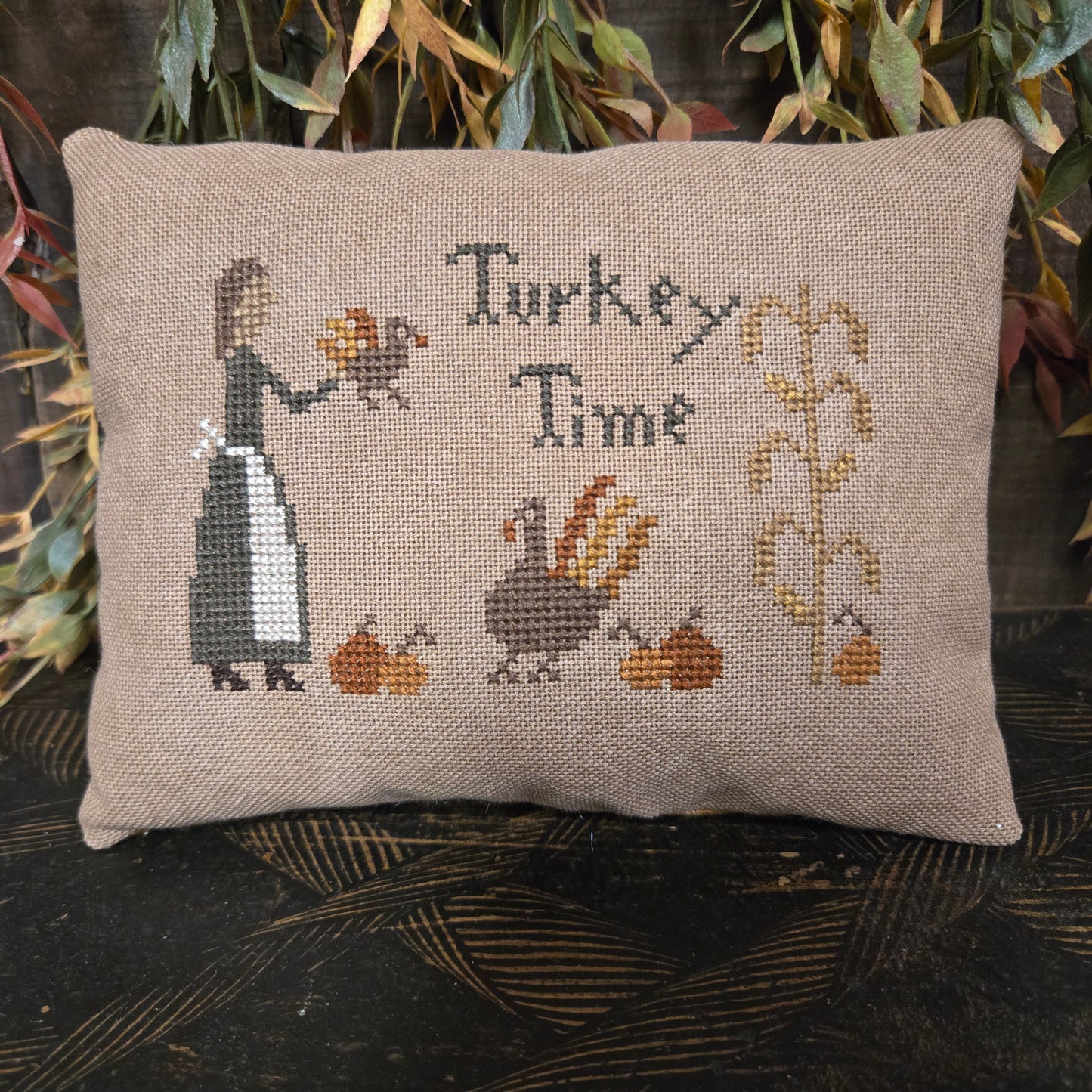 Cross-stitched pillow with 'Turkey Time' text and illustrations on a textured surface.