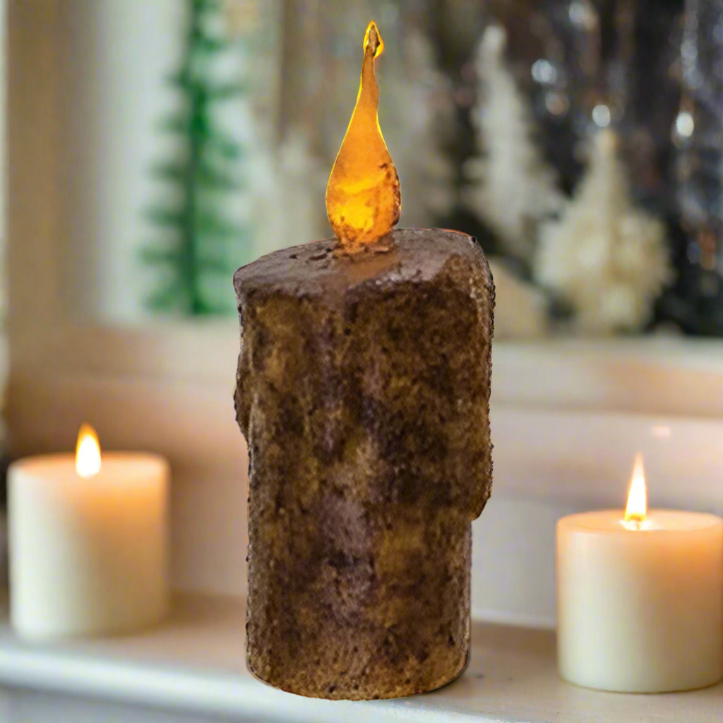 Decorative candle holder with a glowing top on a surface with two other candles.
