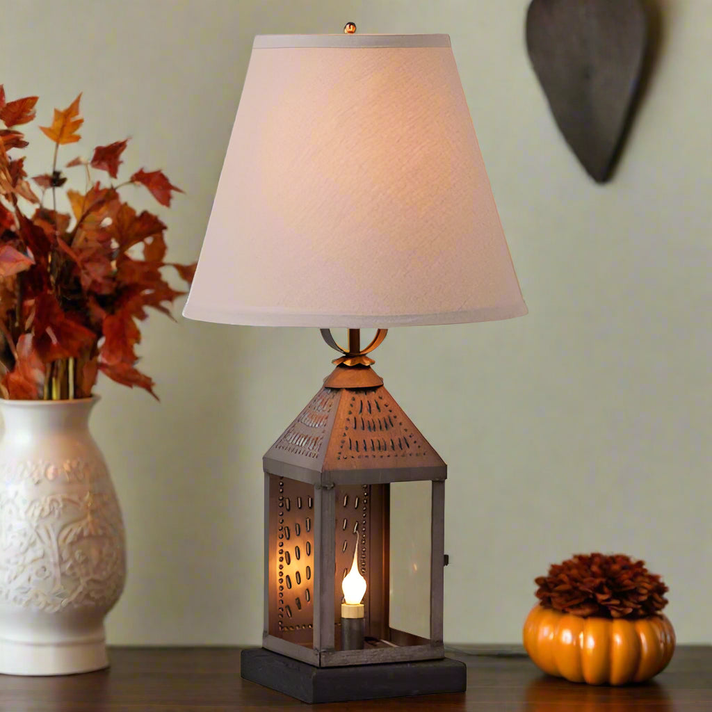Table lamp with decorative metal base and beige shade on a white background