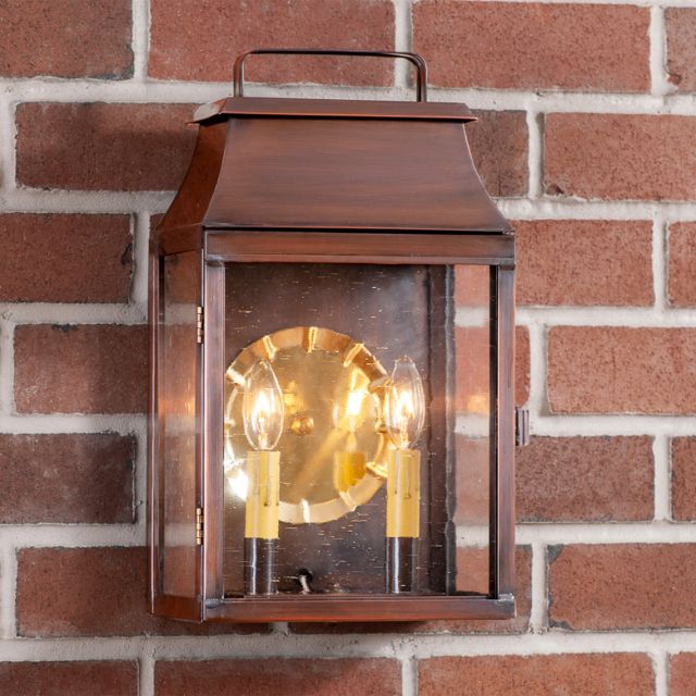 Decorative wall lantern with glass cover on a brick wall