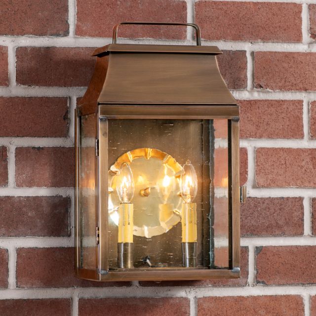 Bronze outdoor wall lantern with glass cover on a brick wall