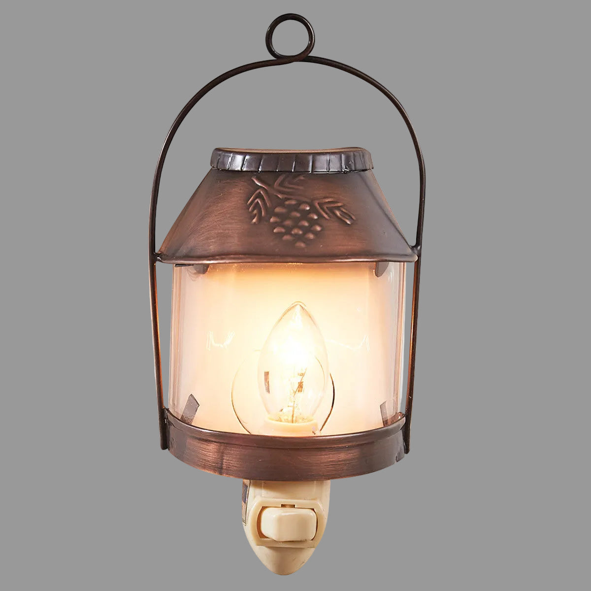 A brown, rustic style Valley Pine Night Light with a pinecone design on the top and a lit lamp inside.