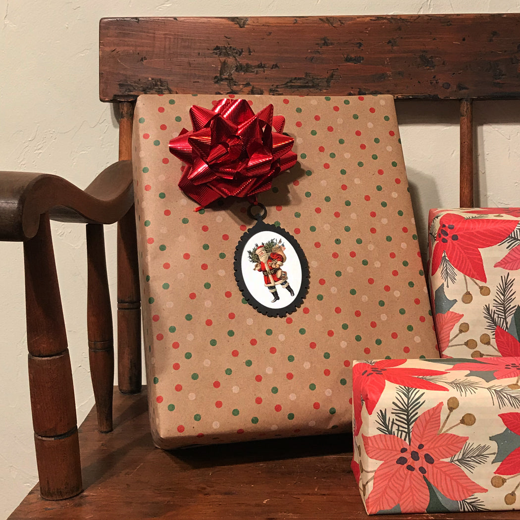 Gift wrapped in brown paper with red polka dots and a red bow, placed on a wooden surface.