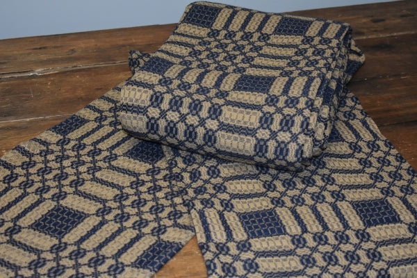 A folded blue and tan geometric patterned table runner placed on a wooden surface.