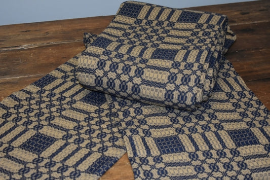 A folded blue and tan geometric patterned table runner placed on a wooden surface.
