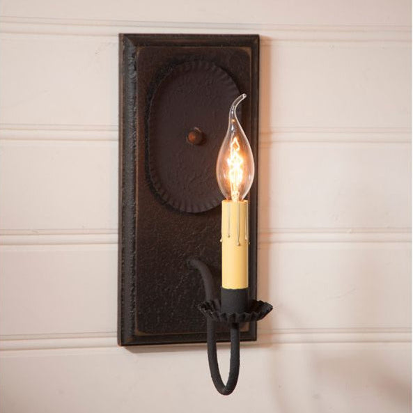 Decorative wall sconce with a lit bulb on a neutral wall background