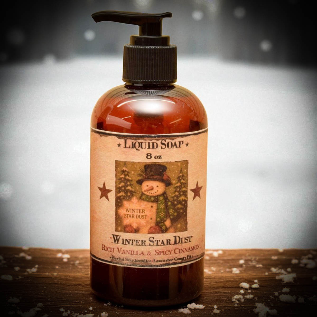 Bottle of liquid soap labeled 'Winter Star Dust' with a snowman design on a wooden surface.
