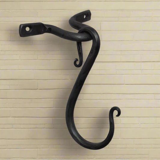 A wrought iron ceiling/wall hook with a curved design, black in color, with mounting holes on the top.