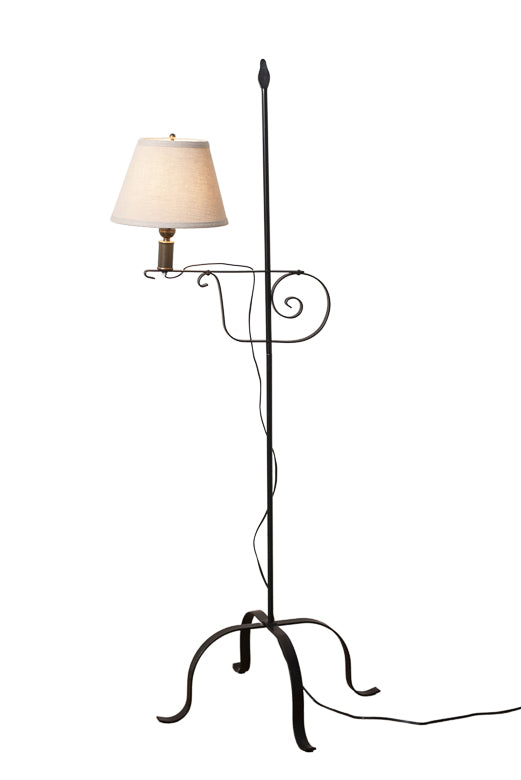An ivory linen shade on a wrought iron floor light, displaying a lamp with a bulb encased in a matching wrought iron holder.