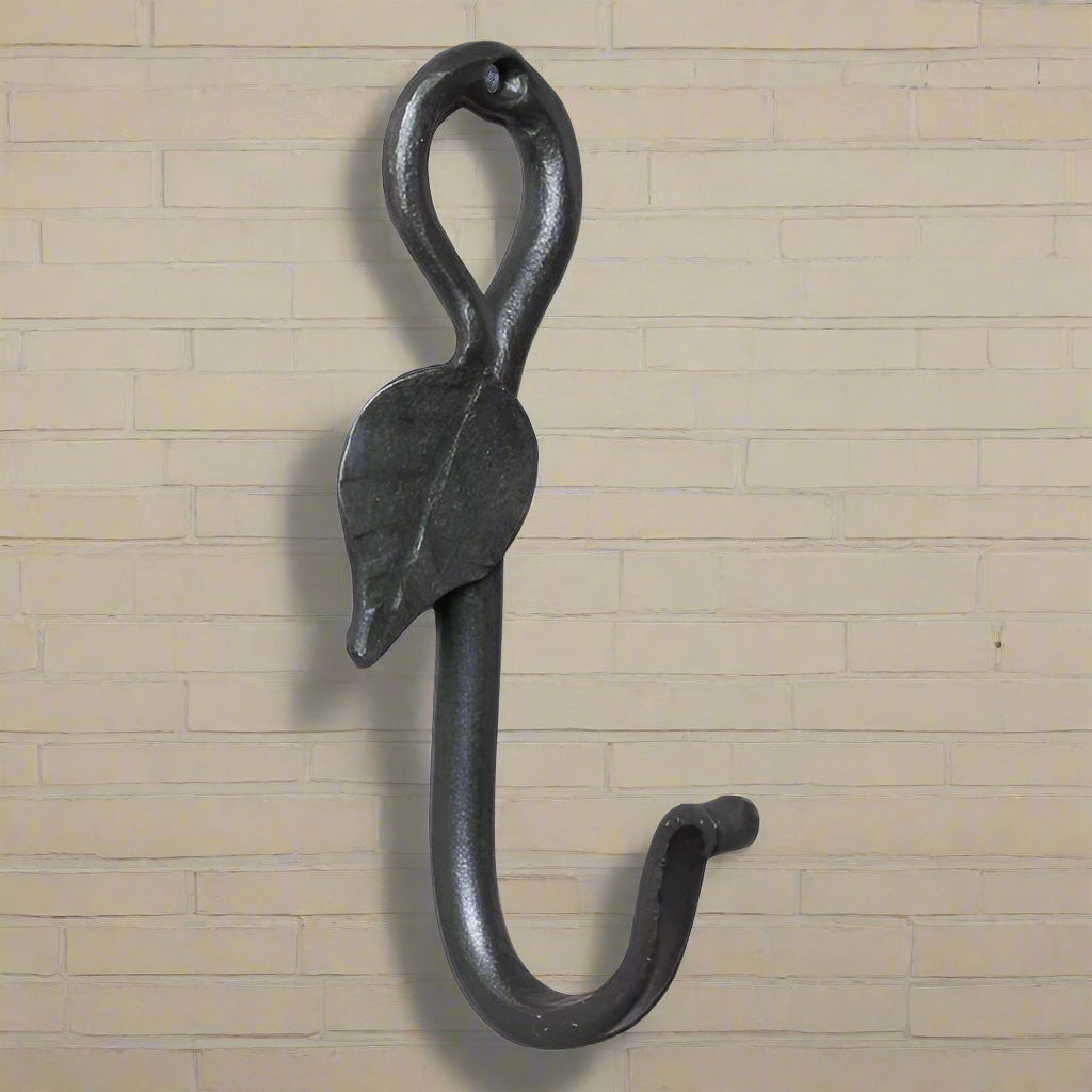 A wrought iron leaf-shaped wall hook with an antique finish, designed for hanging coats or decoration.
