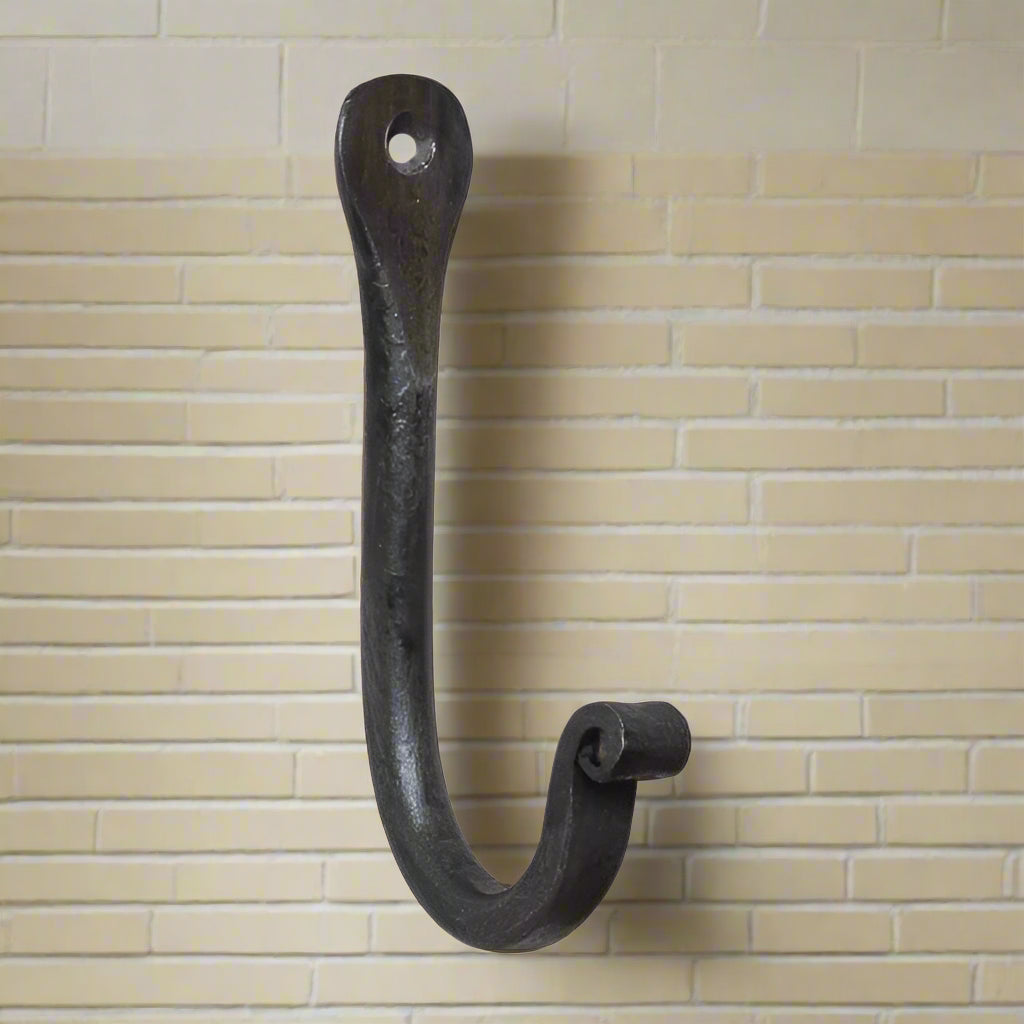 A wrought iron wall hook with an antique finish, designed for hanging items such as hats or towels.