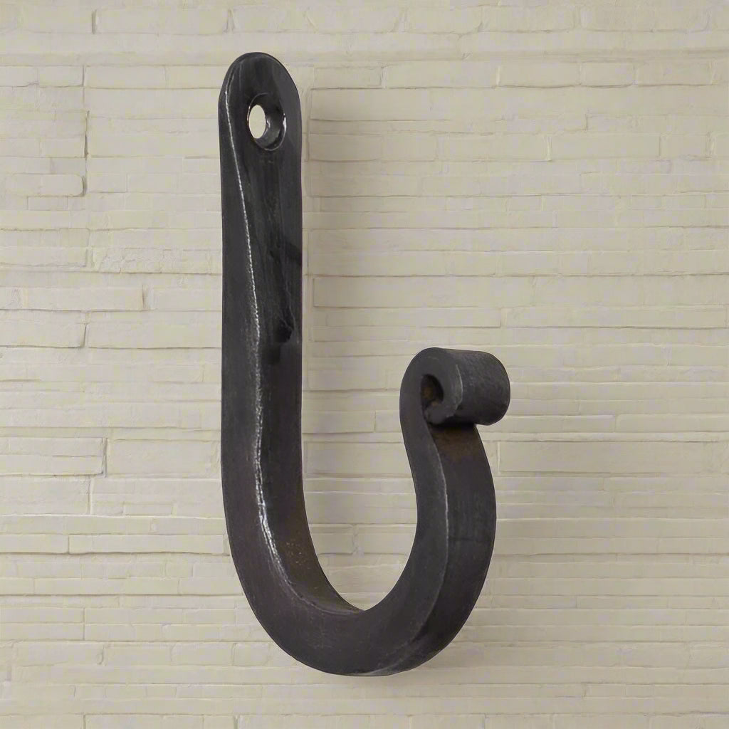 A wrought iron wall hook with a black antique finish, featuring a curved hook and a mounting hole at the top.
