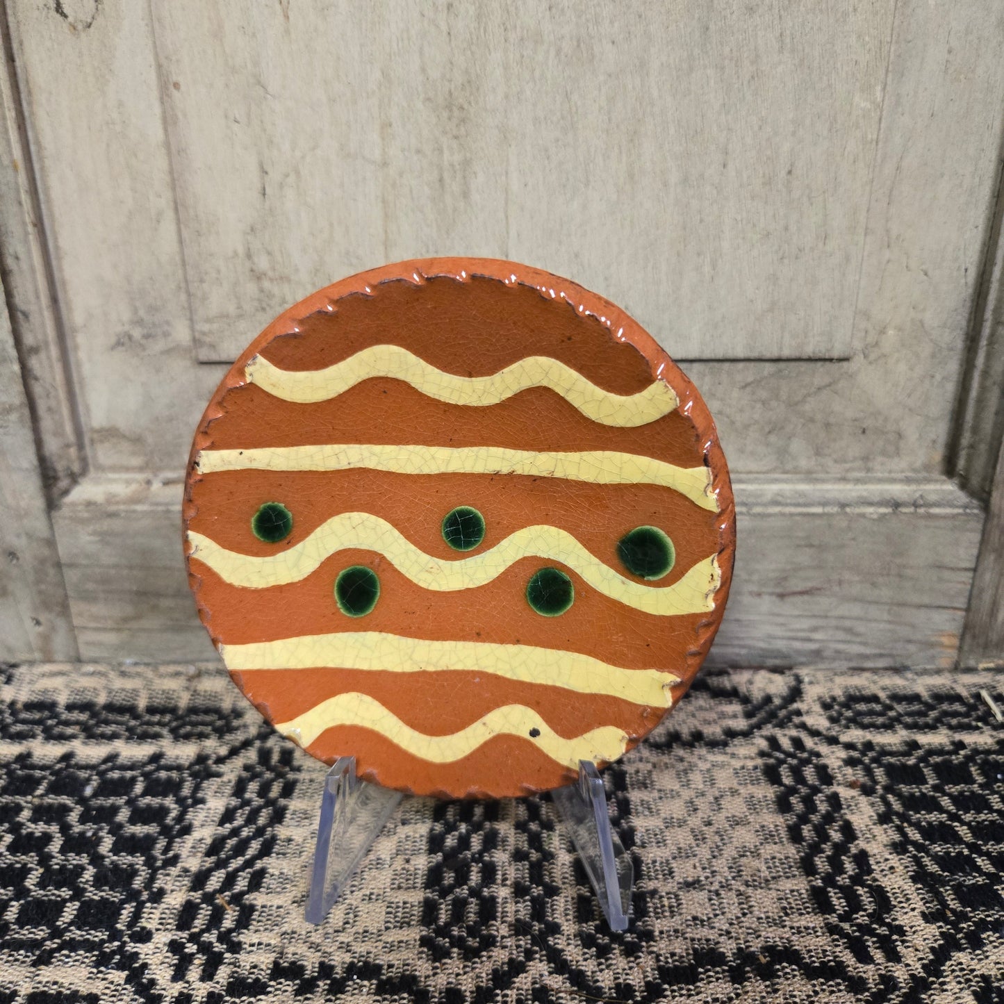 Small round redware plate with yellow lines and green dots