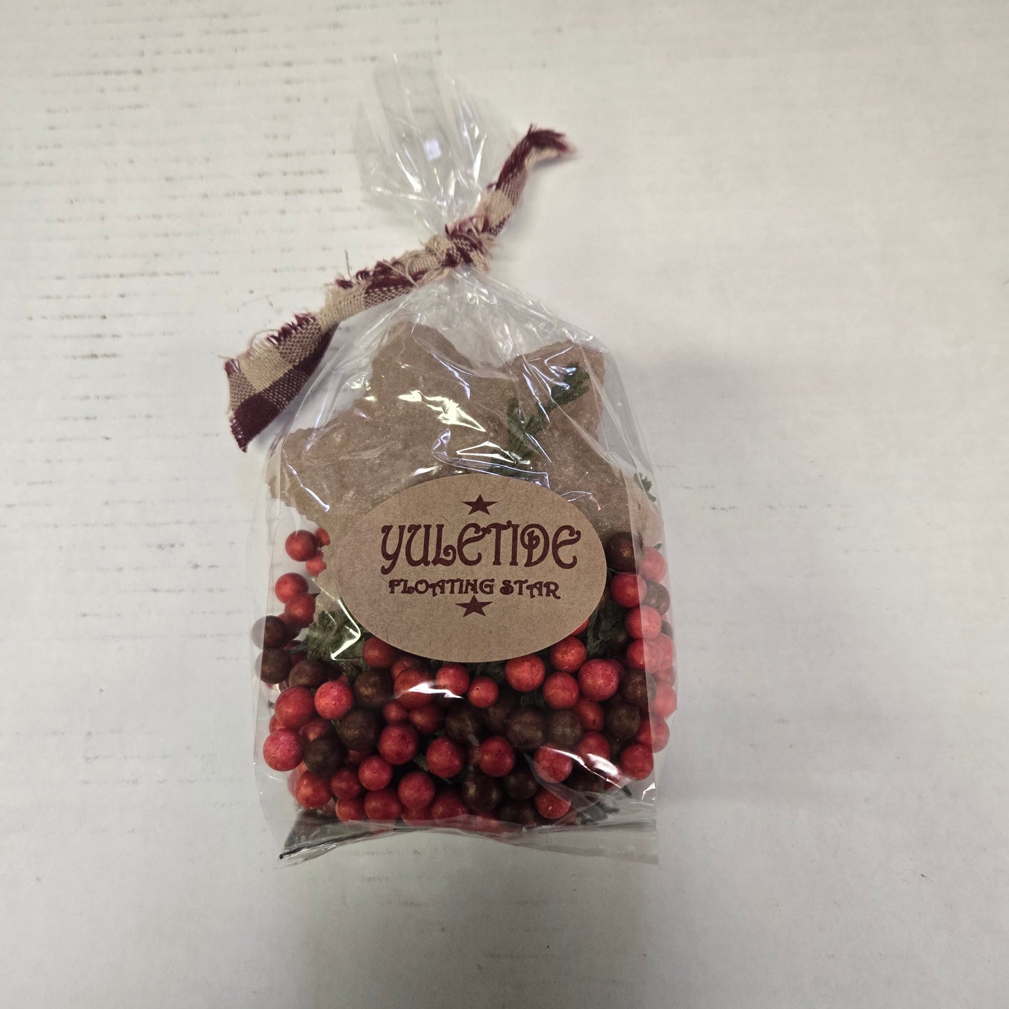 Packaged product with red berries and a decorative tag on a light background