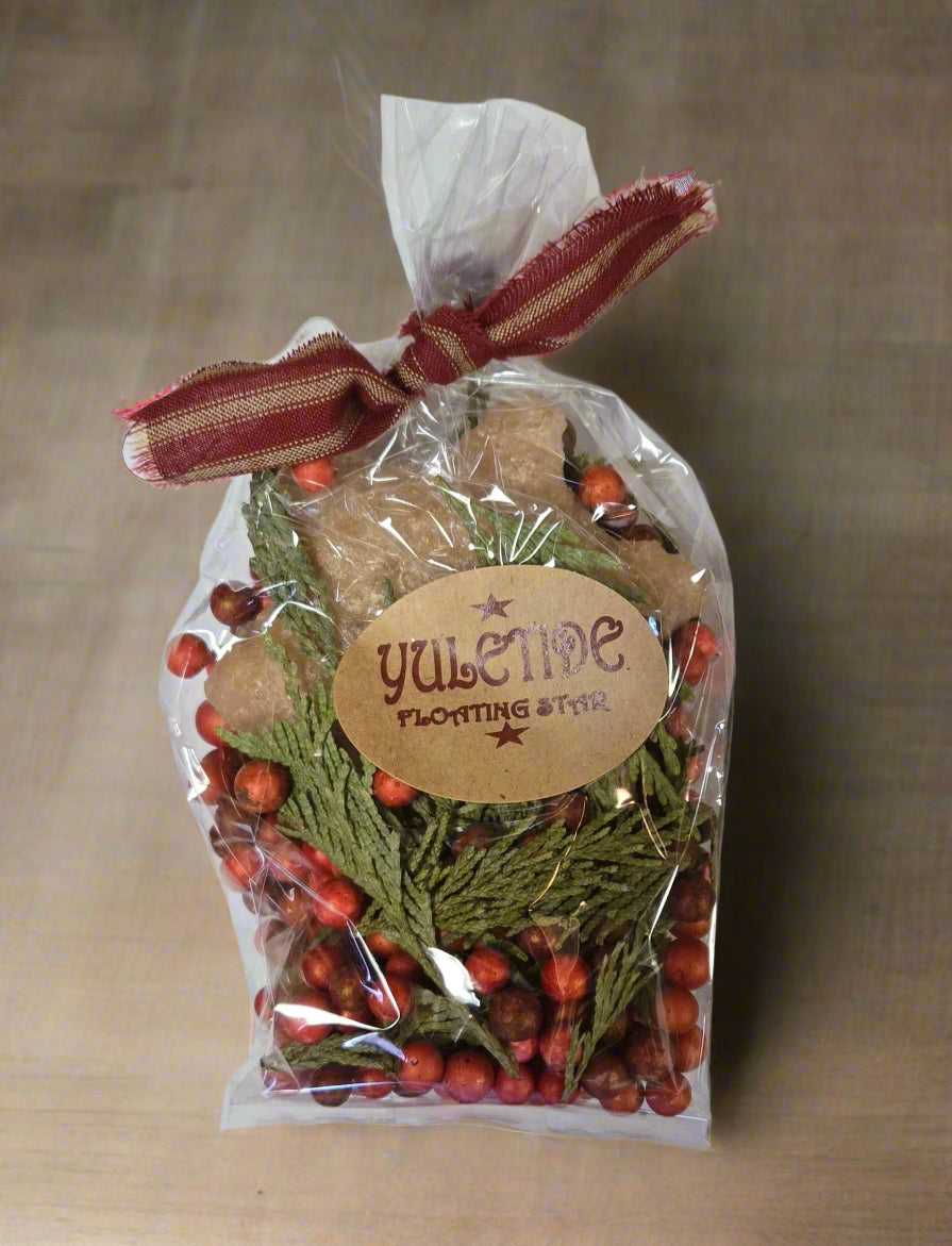 A packaged Yuletide floating candle kit with red berries and green foliage, tied with a ribbon.