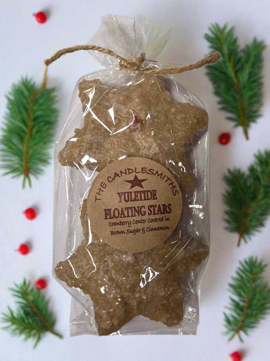 Two small star-shaped floating candles with cranberry center, dipped in brown sugar frosting, packaged in clear plastic wrapping with a twine tie and a label.