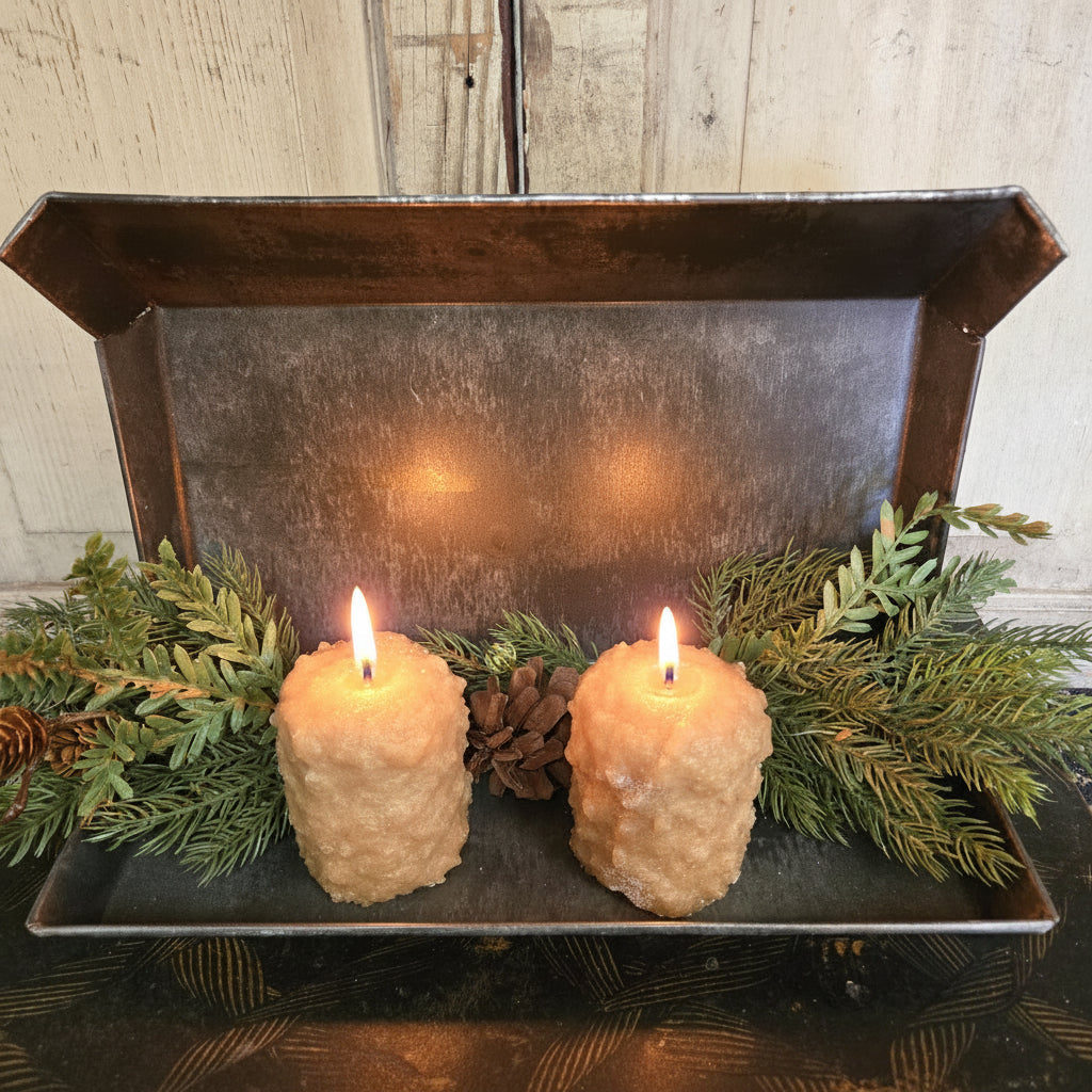Decorative tray with two beige spherical objects and greenery on a wooden surface