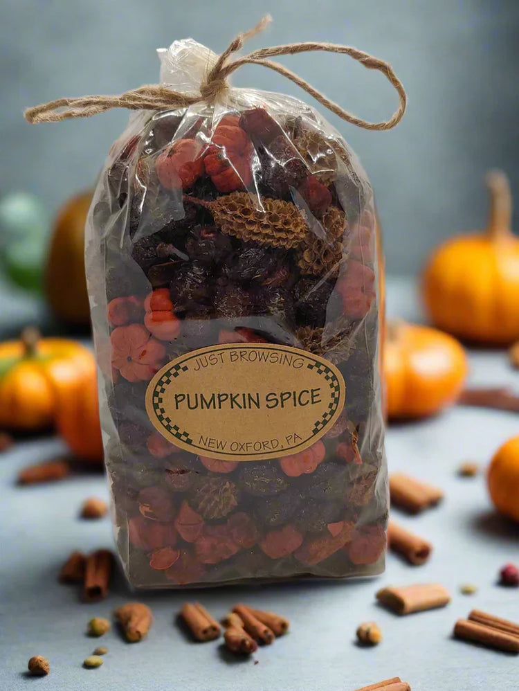 Clear packaging of potpourri surrounded by pumpkins and cinnamon sticks