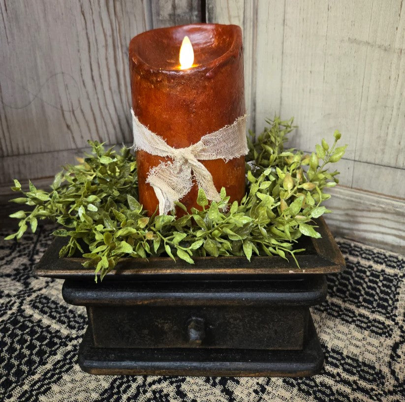 Primitive moving flame candle on a black riser with a green candle ring