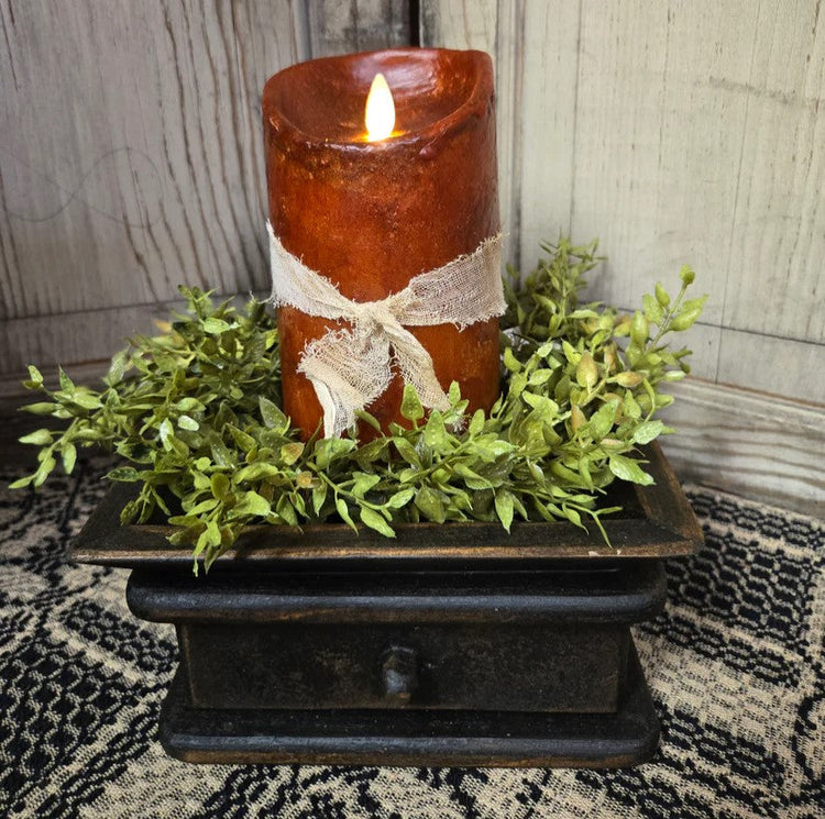 Primitive moving flame candle on a black riser with a green candle ring