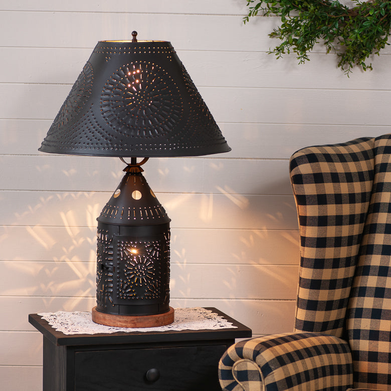 Decorative black lamp on a side table with a plaid chair in the background