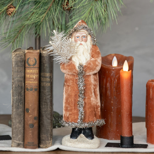 Decorative figure of a bearded man in a brown coat with candles and books on a table.