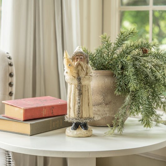 Decorative figure of a fox and a person with a plant and books on a table.