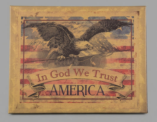Decorative sign with an eagle, American flag, and 'In God We Trust' text on a wooden surface.