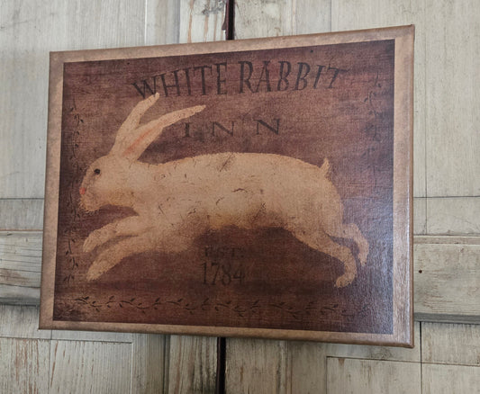 A canvas print with the image of a white rabbit and the text 'WHITE RABBIT INN' on a rustic background.