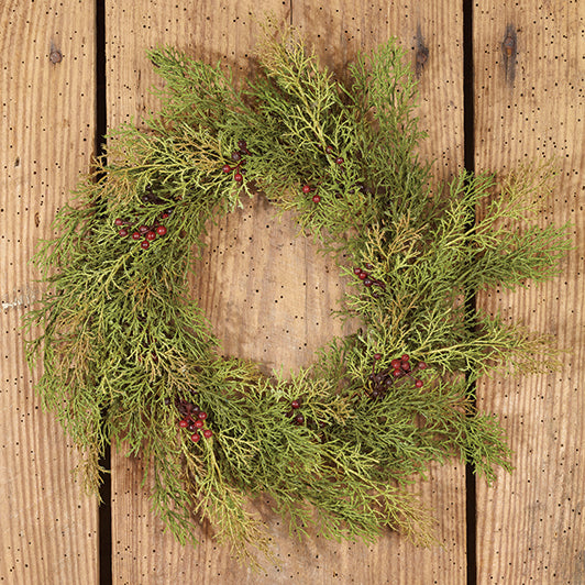 Large candle ring wreath made of artificial cedar branches and red berries