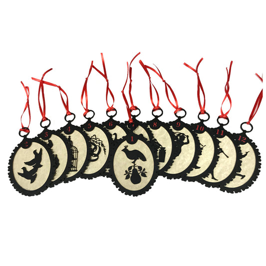 A set of twelve circular silhouette ornaments with red ribbons and black backgrounds, featuring various designs such as a partridge in a pear tree and the text '12 DAYS'.