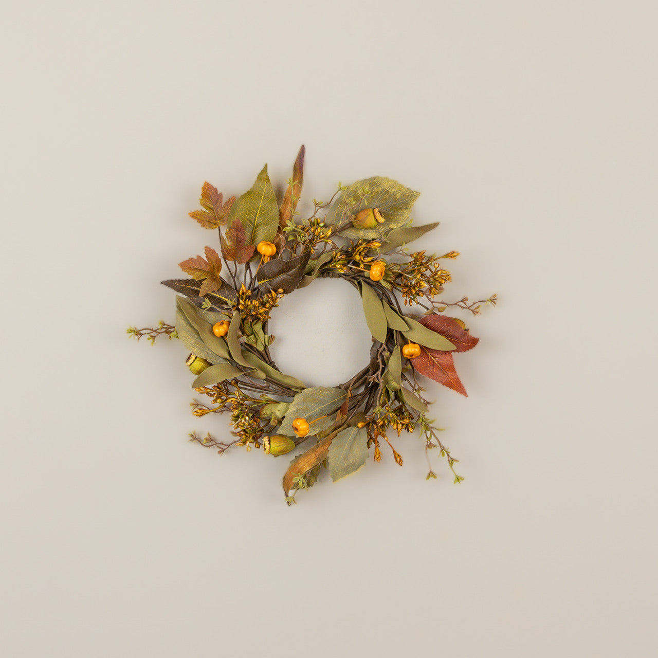 Decorative wreath with autumn leaves and berries on a beige background