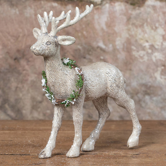 Standing reindeer with wreath on wood surface.