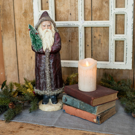 A 17-inch vintage red belsnickle figurine standing next to a holiday-themed candle on a bookshelf, with a festive wreath and ornaments in the background.