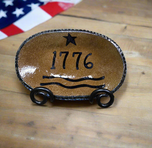 Decorative stone plaque with '1776' and star design on a textured surface.