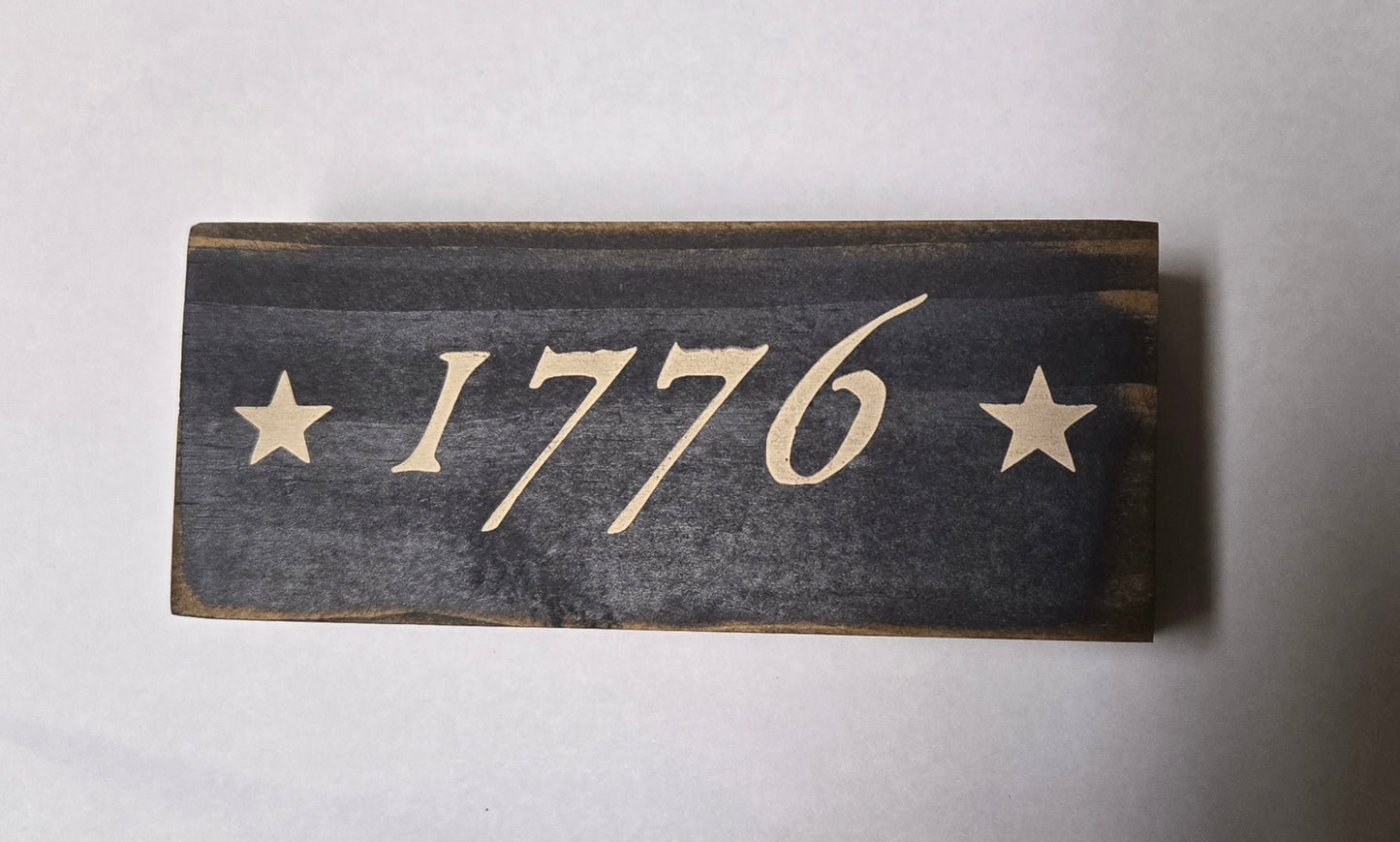 Wooden sign with '1776' and stars on a white background