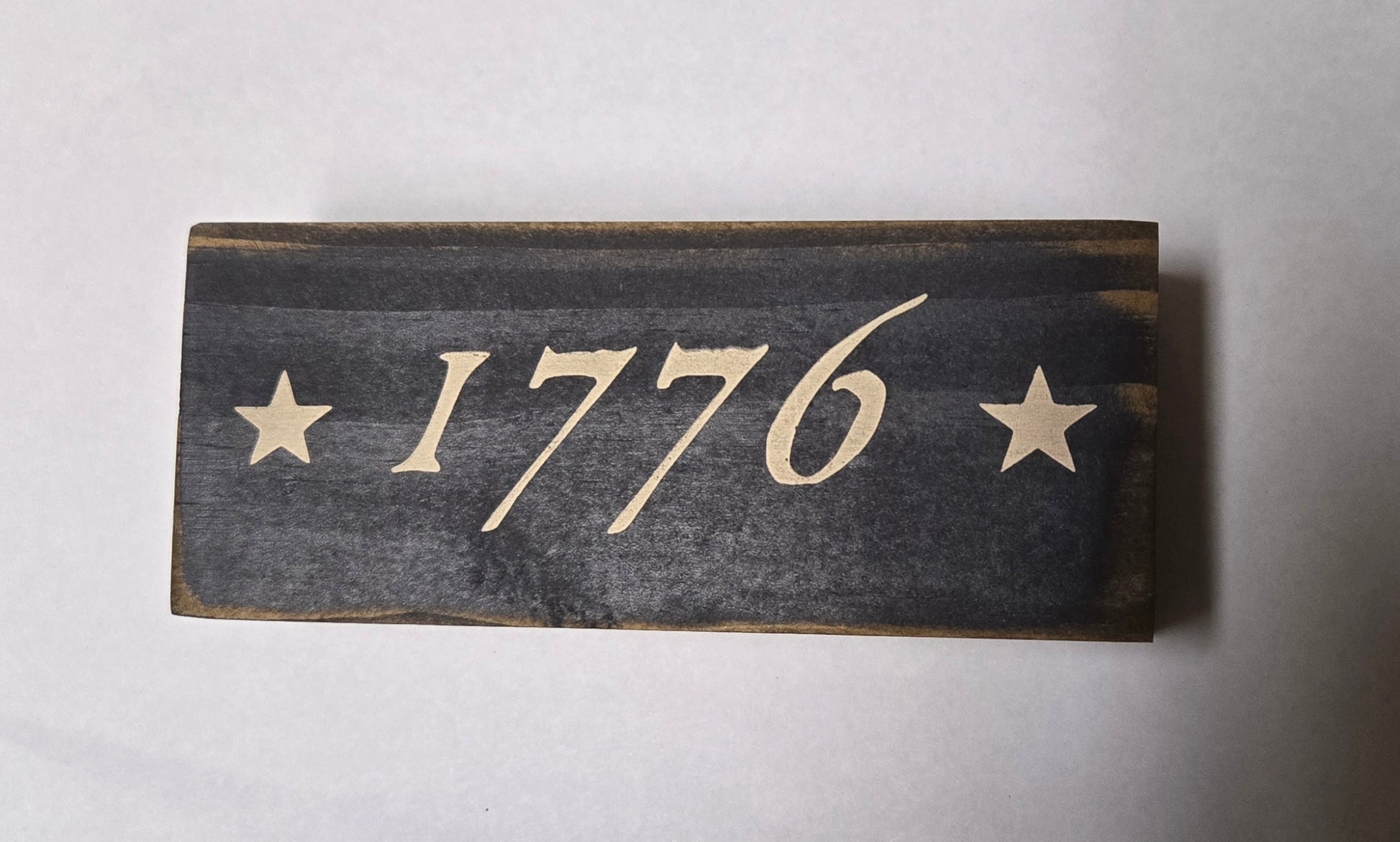 Wooden sign with '1776' and stars on a white background