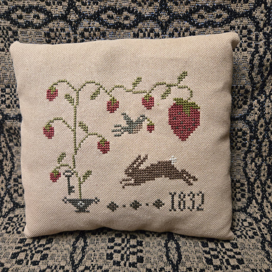 Decorative pillow with embroidered design of a fox and roses on a textured fabric background