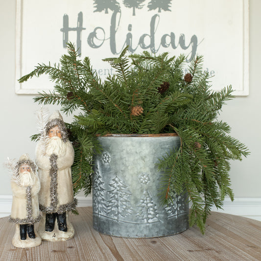 A artificial Douglas Fir holiday wreath with cones, spray-painted green, placed indoors with a 'Happy Holidays' sign in the background.