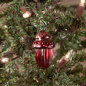 A red acorn-shaped mercury glass ornament hanging on a Christmas tree.