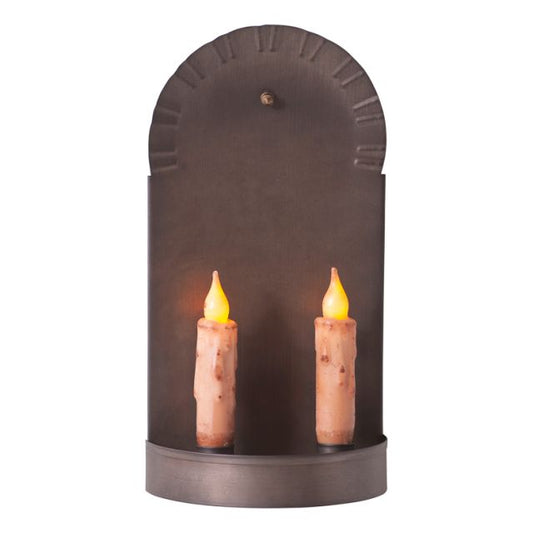 A black metal candle sconce with two candles lit, showing a warm glow.