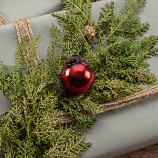 Red mercury ornament on top of gift box with greenery