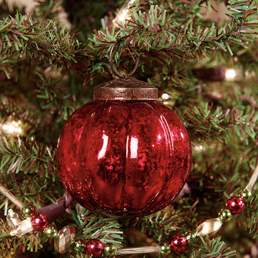 A 2-inch red ridged mercury ornament hanging on a Christmas tree with green branches and red lights.